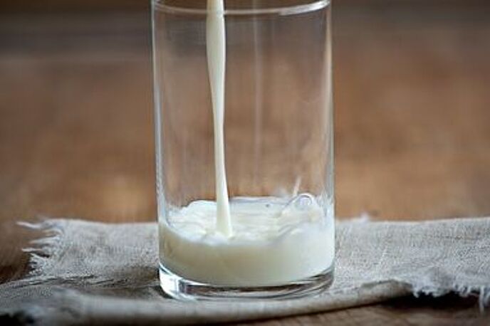 Milch wird in Glas eingeschenkt