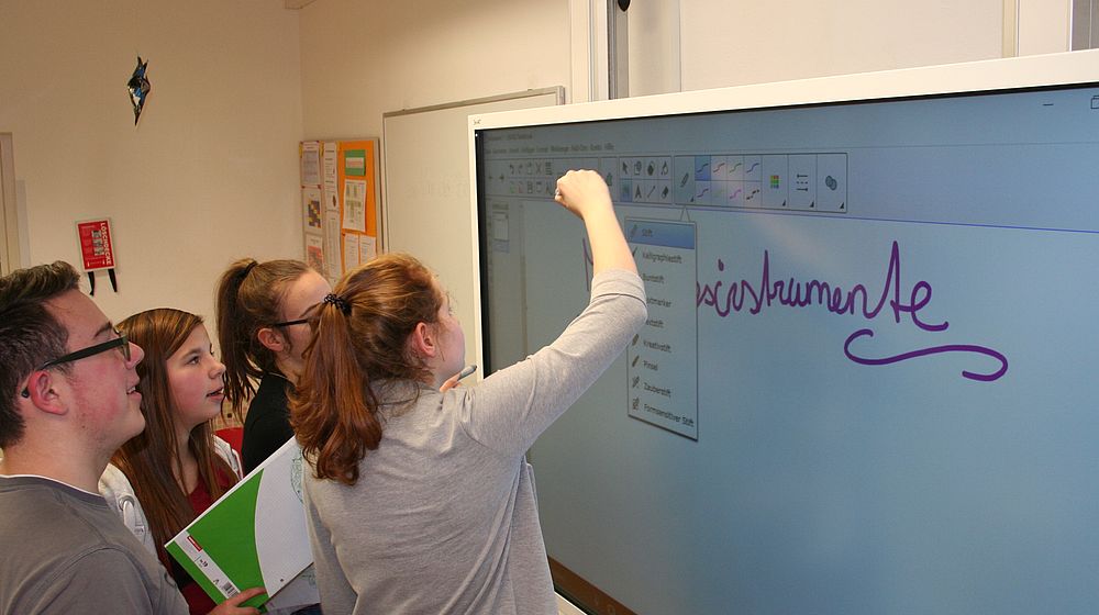 Schülerinnen und Schüler arbeiten gemeinsam am interaktiven Whiteboard