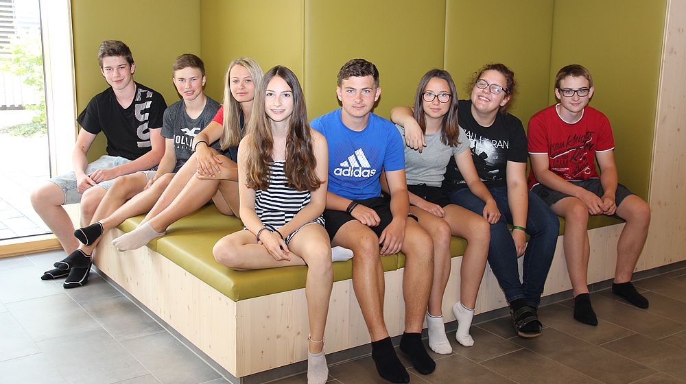 Schülerinnen und Schüler sitzen gemeinsam auf Sitzbank im Internat
