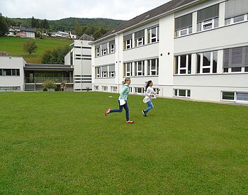 Grünfläche mit Schulgebäude im Hintergrund