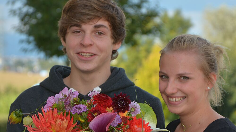 Schülerin und Schüler präsentieren einen Blumenstrauß