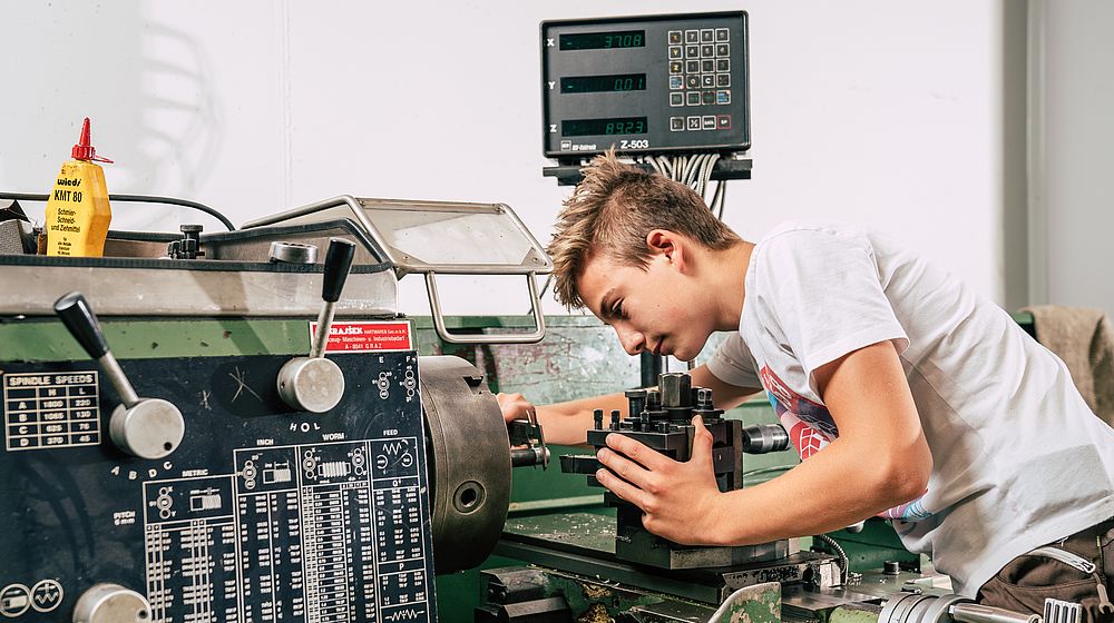 Schüler schraubt an einer Maschine in der Werkstätte