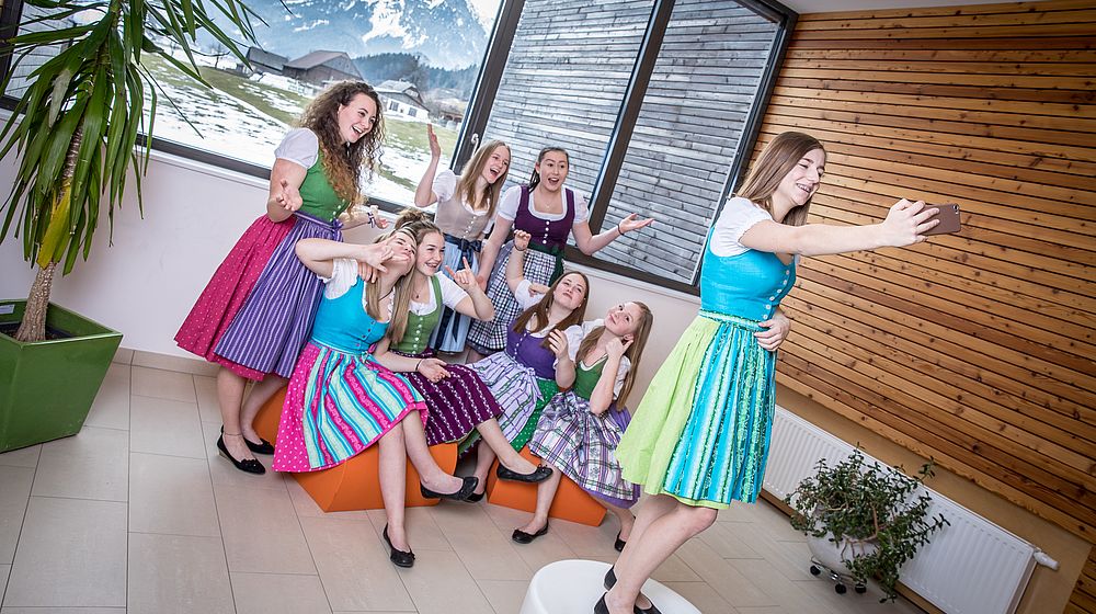 Schülerinnen machen ein Selfie vor Fensterfront in der Schule