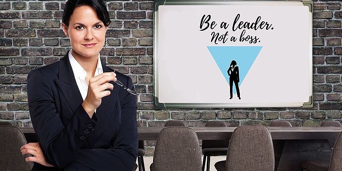 (cc) Gerd Altmann - Pixabay Eine weibliche Führungskraft in einem Besprechungsraum mit einer Ziegelwand, auf der Tafel steht "Be a leader not a boss".