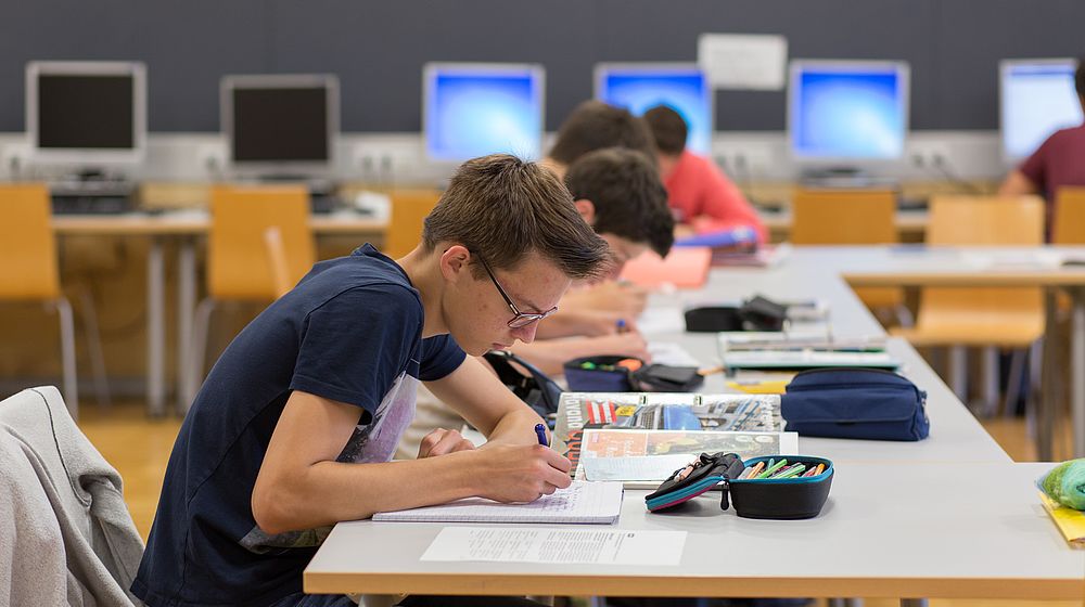 Schülerinnen und Schüler sitzen bei Aufgabe im Computerraum