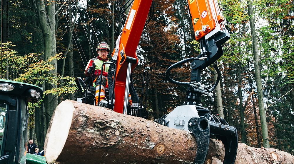 Schüler bedient einen Holzkrananhänger im Wald