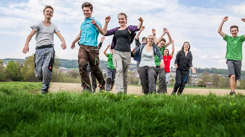 Schülerinnen und Schüler laufen über Wiese