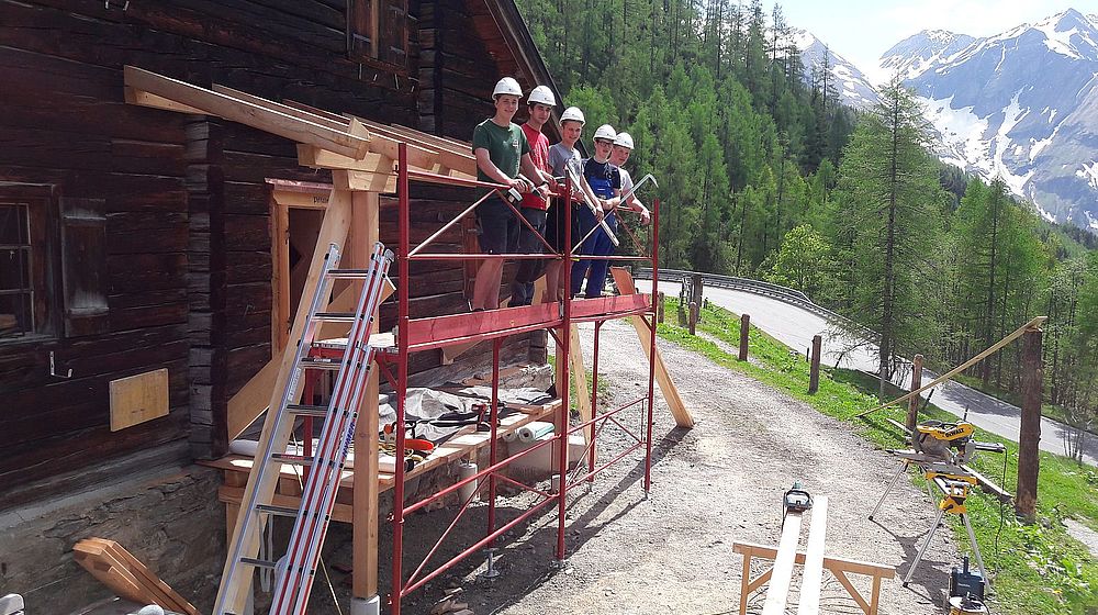 Schüler stehen auf Gerüst vor Hausfassade