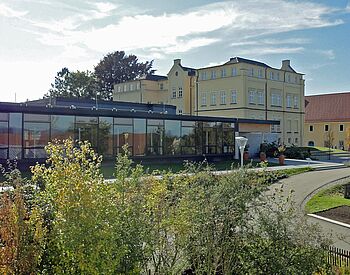 Modernes Glasgebäude mit historischem Schloss im Hintergrund