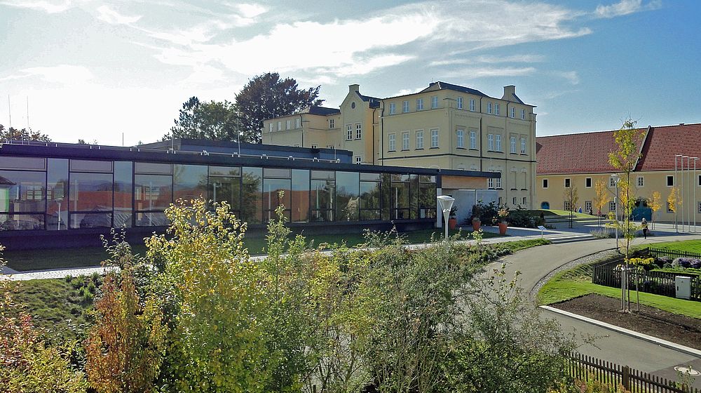 Modernes Glasgebäude mit historischem Schloss im Hintergrund