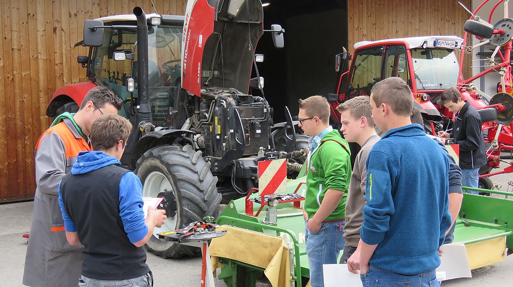 Schülergruppe vor landwirtschaftlichen Maschinen und Traktoren