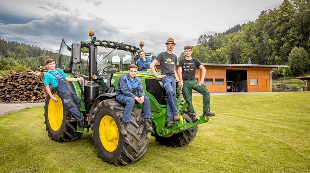 Schüler posieren auf einem Traktor