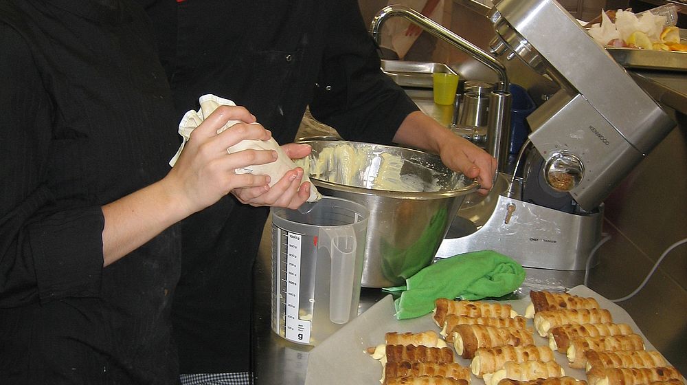 Schülerinnen und Schüler machen Schaumrollen in der Lehrküche