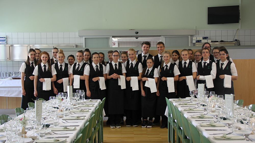 Schülerinnen und Schüler machen ein Gruppenfoto im gedeckten Speisesaal