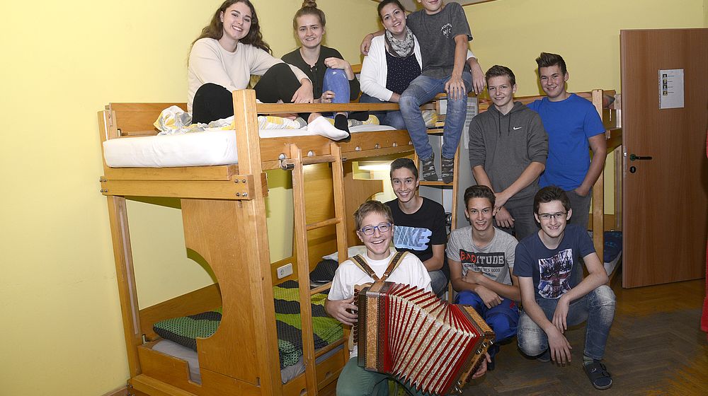 Gruppe von Schülerinnen und Schüler mit Steirischer Harmonika im Internatszimmer
