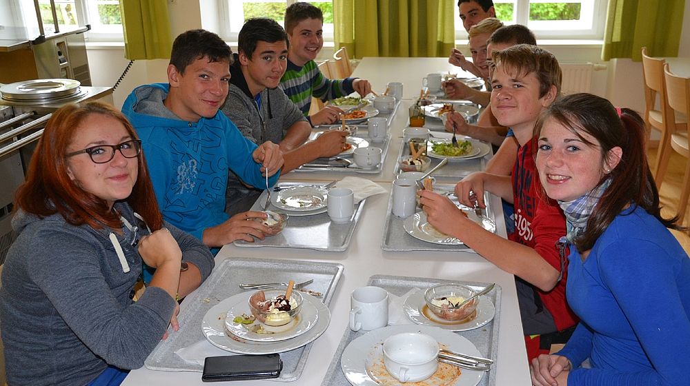 Schülerinnen und Schüler sitzen am Tisch beim gemeinsamen Mittagessen