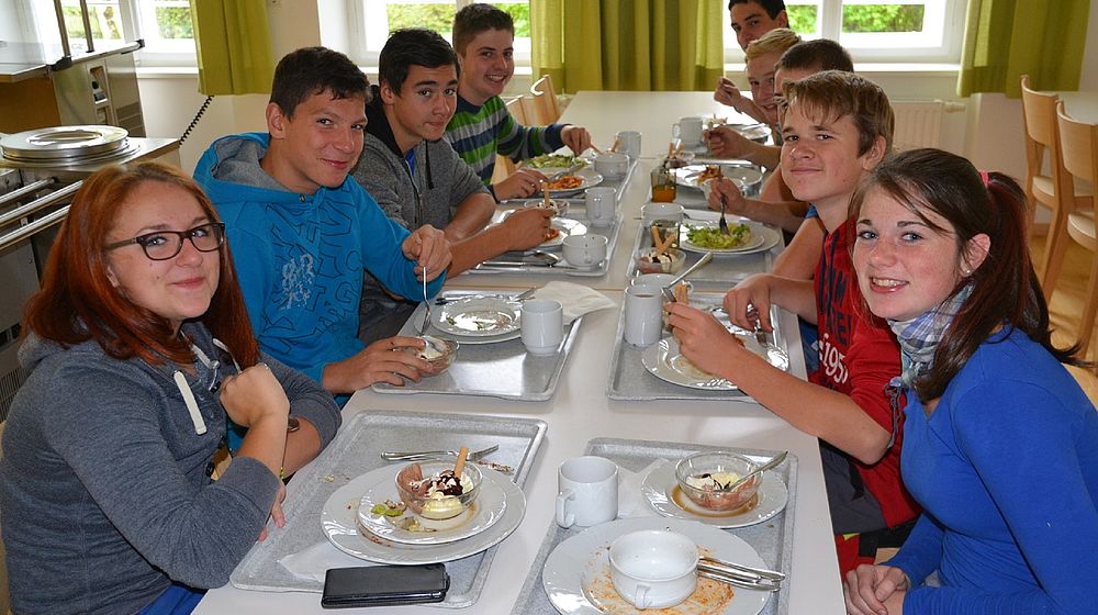 Schülerinnen und Schüler sitzen am Tisch beim gemeinsamen Mittagessen