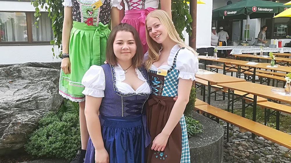 Schülerinnen stehen vor der Schule im Dirndl