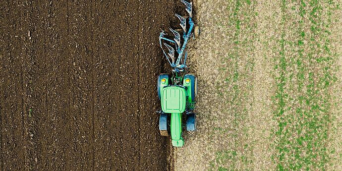 ©Julia Koblitz | Unsplash ein Traktor pflügt ein Grasfeld