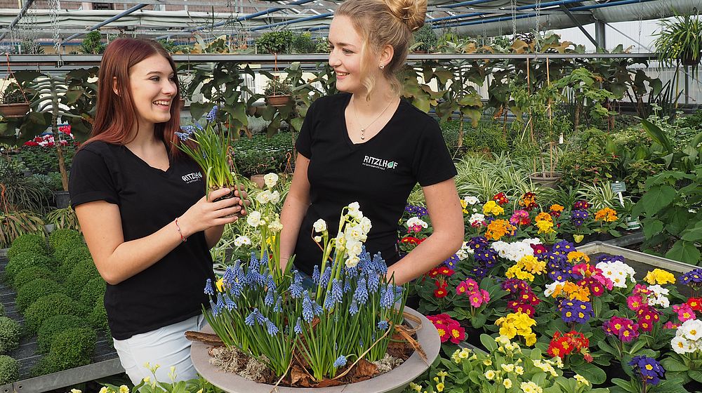 Schülerinnen im Glashaus beim Arbeiten mit Blumen