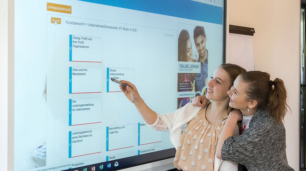 Schülerinnen arbeiten zu zweit am interaktiven Whiteboard