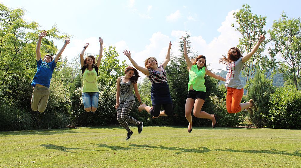 Schülerinnen und Schüler springen in die Luft im Grünen