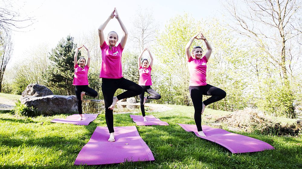 Schülerinnen praktizieren Yoga im Freien