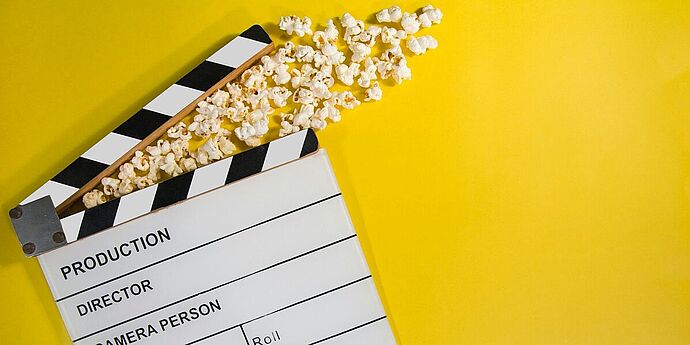 © GR Stocks (Unsplash) Produktionsklappe mit Popcorn auf gelbem Hintergrund