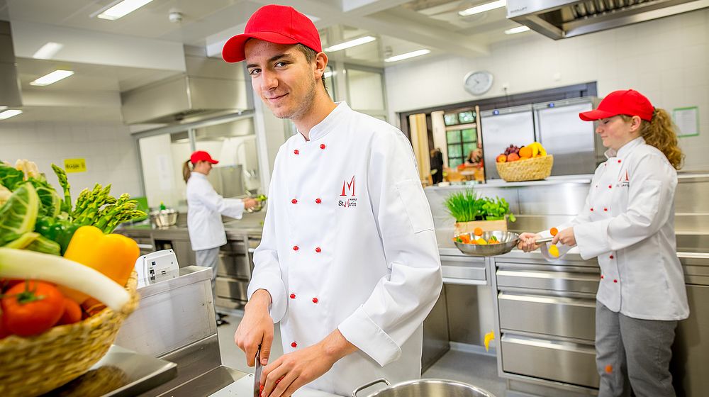 Schüler und Schülerinnen beim Gemüse schneiden und kochen in der Küche