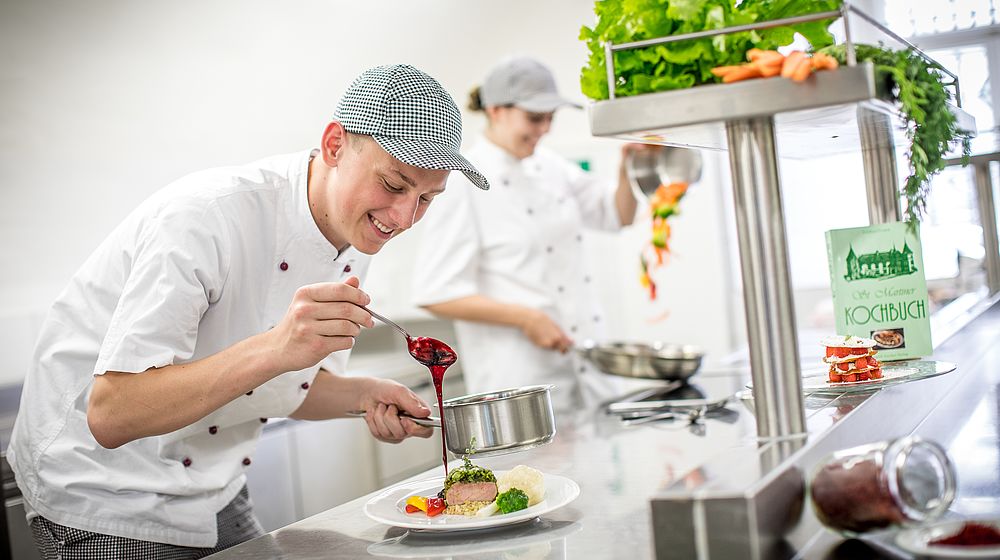 Schüler und Schülerin beim Anrichten ihrer selbst gemachten Gerichte 