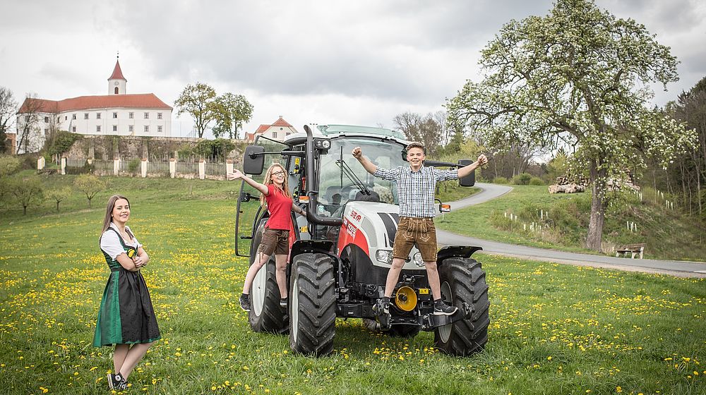 Traktor mit Schüler und Schülerinnen vor Schulgebäude